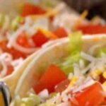 Close Up Of Fresh Tacos With Shredded Cheese, Diced Tomatoes, And Lettuce, Marked With A 