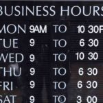 A Business Hours Sign Showing Opening Times For Each Day Of The Week With Varying Closing Hours.